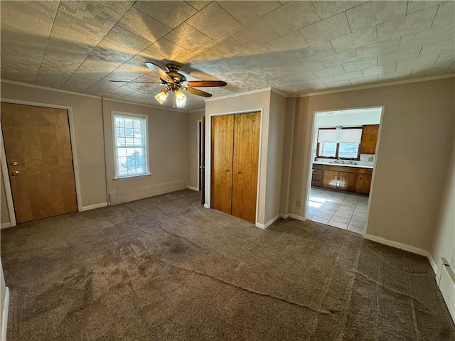 unfurnished bedroom with ensuite bath, baseboards, ornamental molding, and carpet flooring