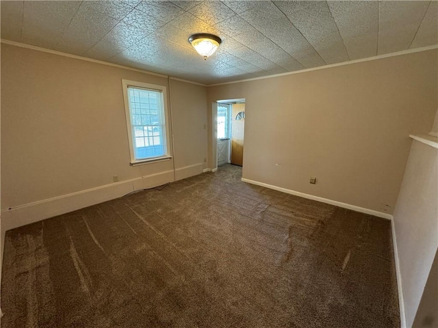 unfurnished room with ornamental molding, dark carpet, and baseboards