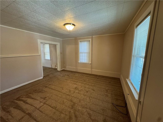 empty room featuring baseboards, carpet floors, a healthy amount of sunlight, and crown molding