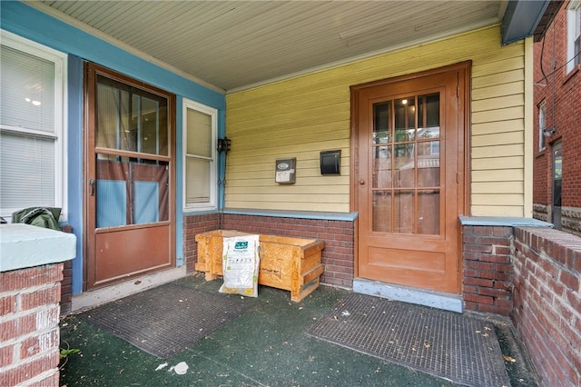 view of exterior entry featuring a porch and brick siding