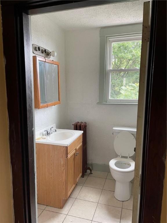 bathroom featuring radiator, toilet, a textured ceiling, vanity, and tile patterned floors