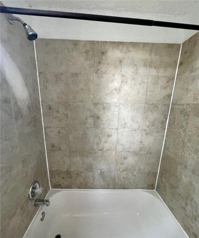 bathroom featuring shower / bathtub combination and a textured ceiling