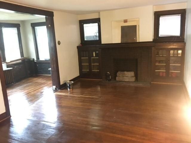 living area featuring a fireplace with raised hearth, wood finished floors, and baseboards