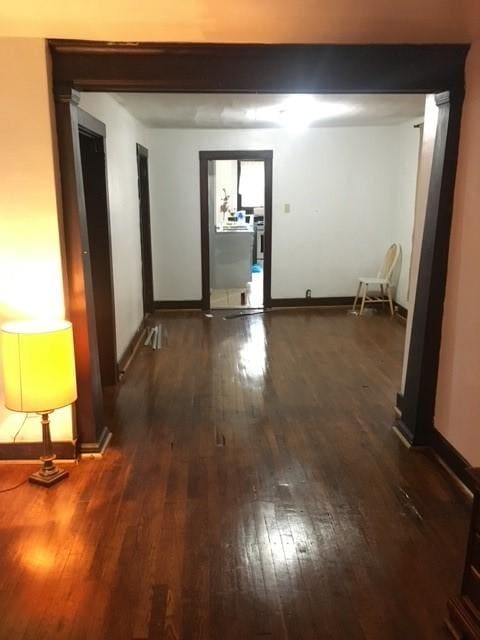 corridor with dark wood-style flooring and baseboards