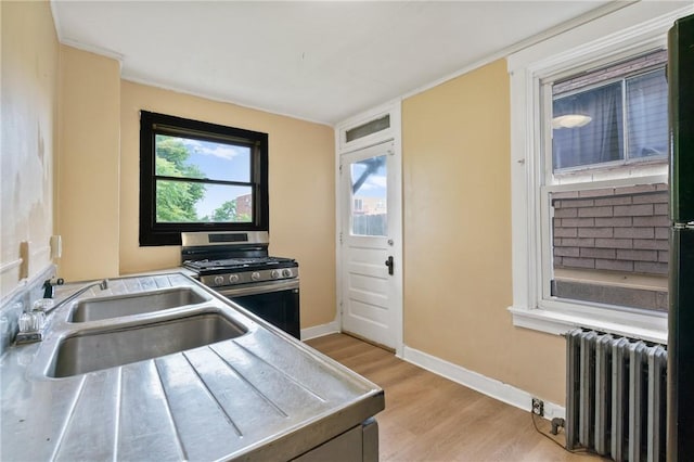 7807 Union Ave, Swissvale, PA 15218 - kitchen with radiator heating unit, stainless steel range with gas stovetop, stainless steel counters, and light wood-type flooring