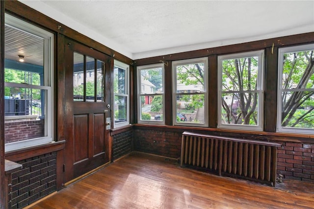 7807 Union Ave, Swissvale, PA 15218 - unfurnished sunroom with radiator, brick wall, wood finished floors, and healthy amount of natural light