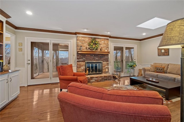 living room with wainscoting, ornamental molding, a fireplace, and a skylight