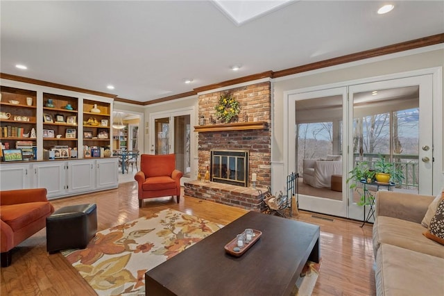 living area featuring light wood finished floors, a brick fireplace, and crown molding