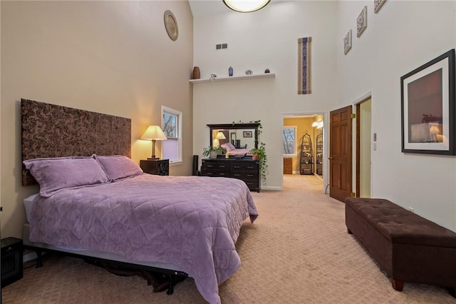 bedroom featuring light carpet, a high ceiling, connected bathroom, and visible vents