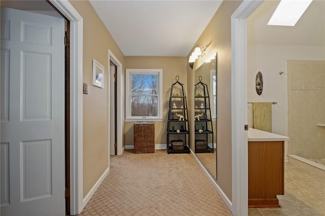 hallway with a skylight and baseboards