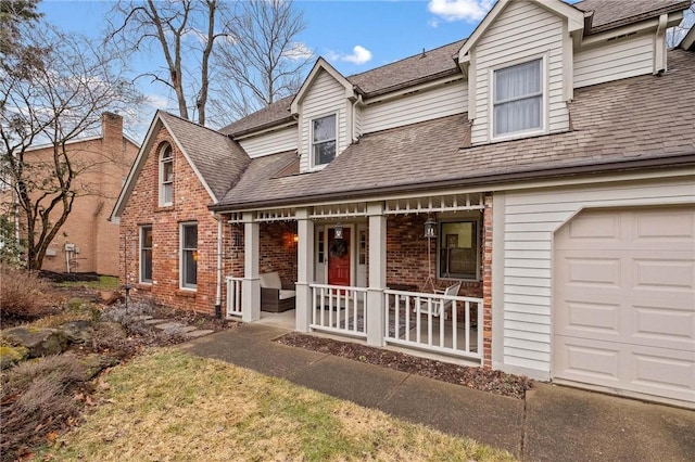 view of front facade featuring a porch, brick siding, a garage, and roof with shingles