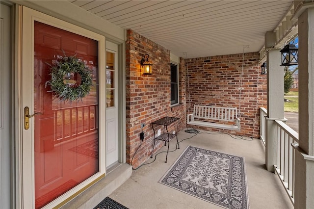 property entrance with a porch and brick siding