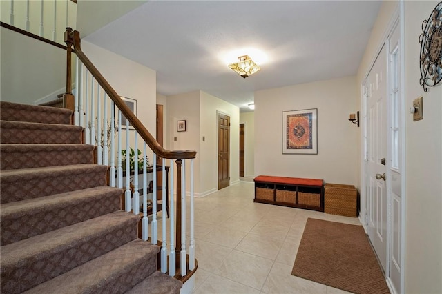 foyer entrance with light tile patterned floors, baseboards, and stairway