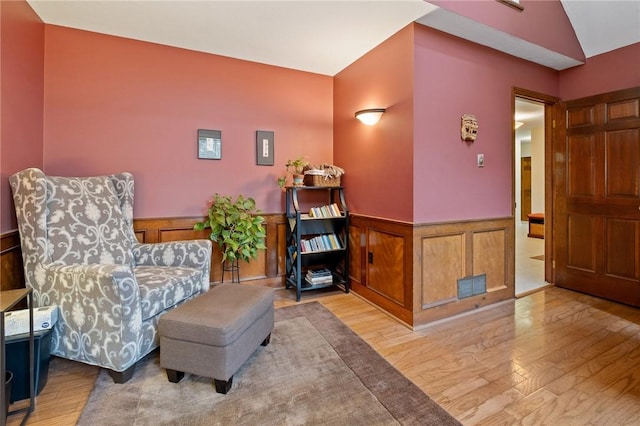 living area featuring wainscoting and wood finished floors