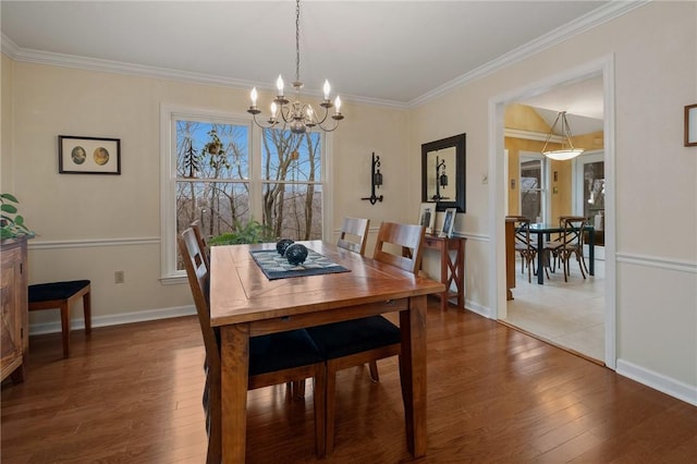 dining space featuring ornamental molding, a notable chandelier, baseboards, and wood finished floors