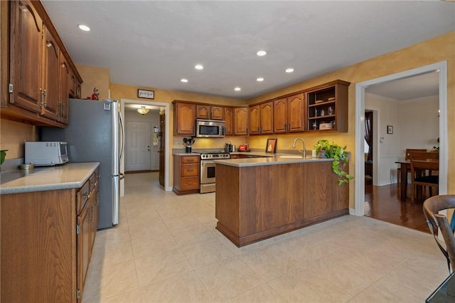 kitchen with open shelves, stainless steel appliances, brown cabinetry, a sink, and a peninsula