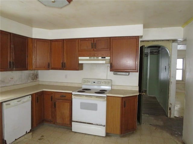 kitchen with light floors, light countertops, brown cabinetry, white appliances, and under cabinet range hood