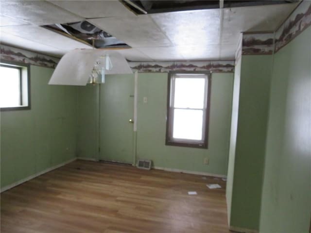 unfurnished room with plenty of natural light, wood finished floors, and visible vents