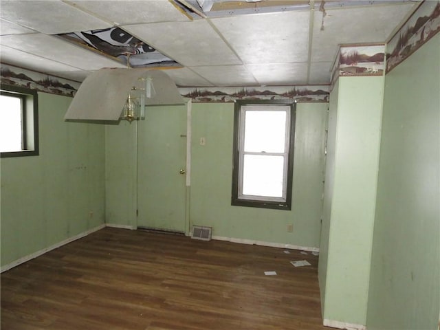 empty room featuring a wealth of natural light, wood finished floors, visible vents, and baseboards