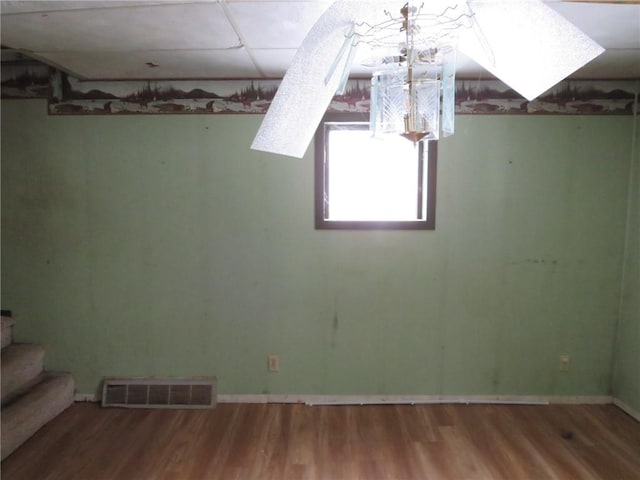 below grade area featuring stairway, baseboards, visible vents, and wood finished floors