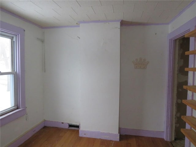 spare room featuring baseboards, wood finished floors, and a healthy amount of sunlight