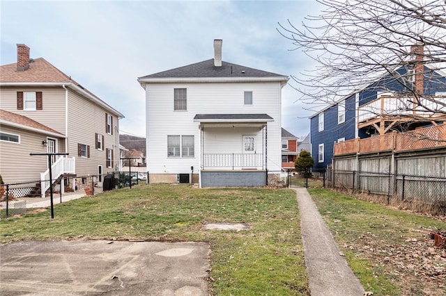 back of house featuring fence, a chimney, and a lawn