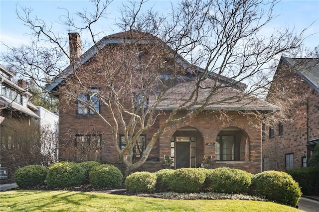 view of front of house with a front yard, brick siding, and a chimney