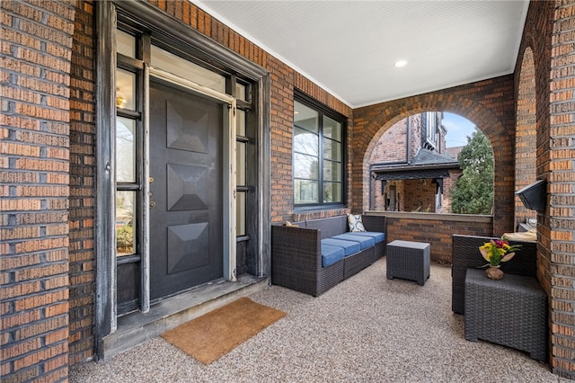 doorway to property featuring an outdoor hangout area, brick siding, and covered porch