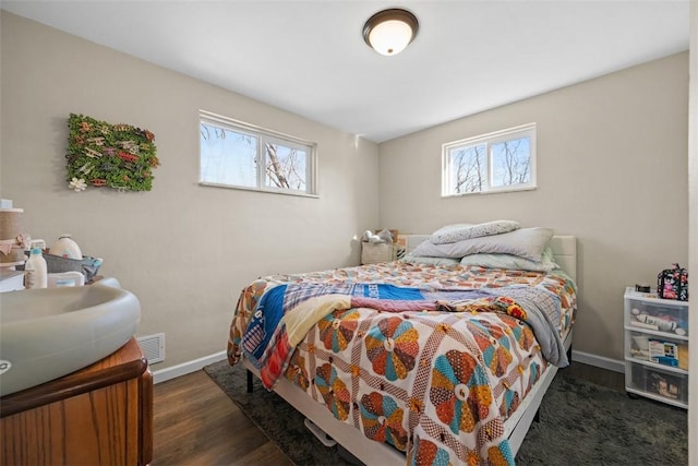 bedroom featuring dark wood-type flooring, multiple windows, visible vents, and baseboards