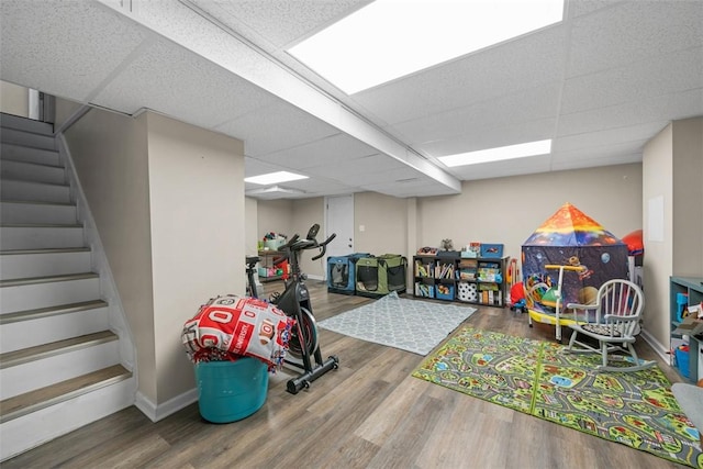 rec room featuring wood finished floors, a paneled ceiling, and baseboards