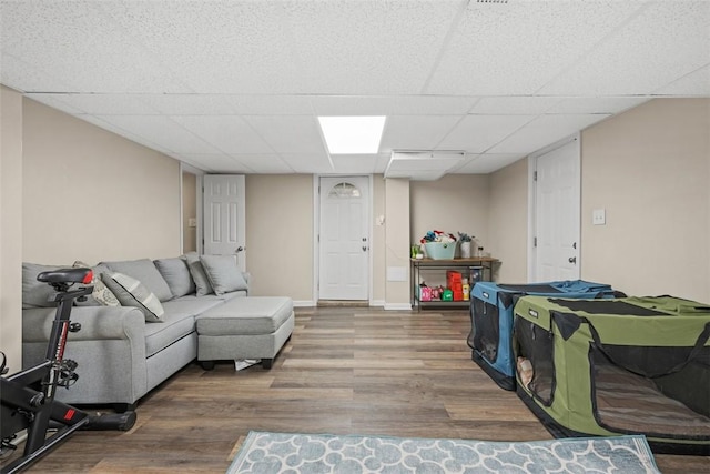 living room with wood finished floors, a paneled ceiling, and baseboards