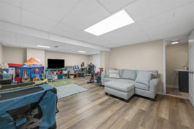 living room with baseboards, a drop ceiling, and wood finished floors