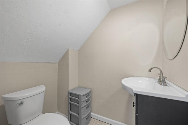 half bathroom featuring toilet, vanity, a textured ceiling, and lofted ceiling