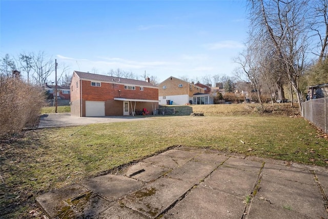 back of house featuring a garage, a yard, driveway, and brick siding