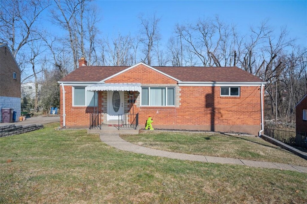 bungalow with roof with shingles, brick siding, a chimney, and a front yard