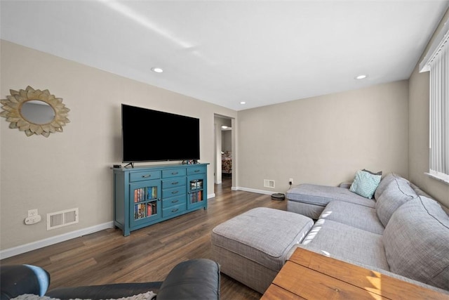 living area with dark wood-type flooring, visible vents, and baseboards