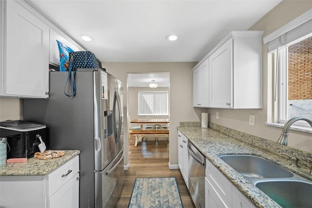 kitchen featuring appliances with stainless steel finishes, a sink, white cabinetry, and a healthy amount of sunlight