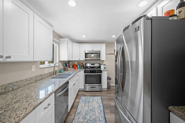 kitchen featuring recessed lighting, stainless steel appliances, a sink, white cabinetry, and dark wood-style floors