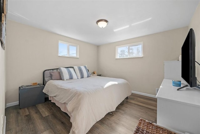 bedroom with multiple windows, baseboards, and wood finished floors