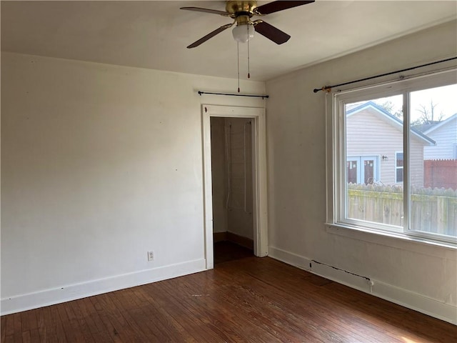 unfurnished room with a ceiling fan, dark wood finished floors, and baseboards