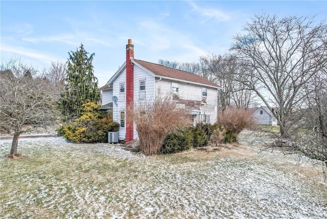 view of home's exterior with a chimney and cooling unit