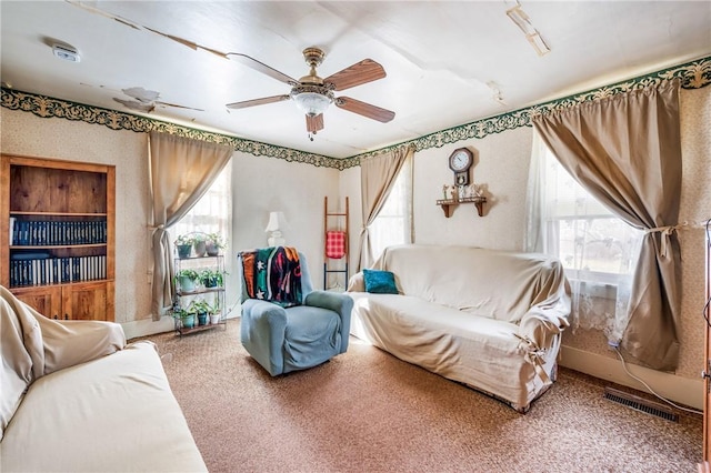 carpeted living room featuring ceiling fan, visible vents, and a wealth of natural light