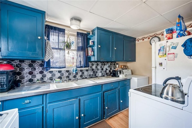 kitchen featuring blue cabinetry, backsplash, stove, freestanding refrigerator, and a sink