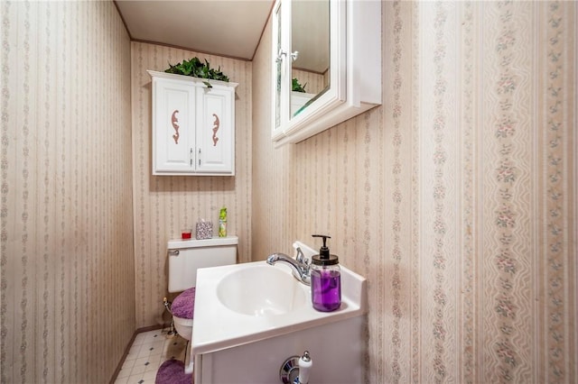 half bath with tile patterned floors, vanity, toilet, and wallpapered walls