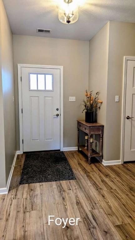 foyer featuring visible vents, baseboards, and wood finished floors