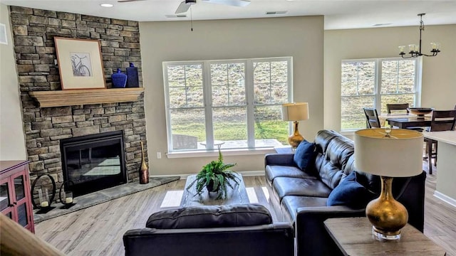 living room featuring a wealth of natural light, a stone fireplace, and wood finished floors