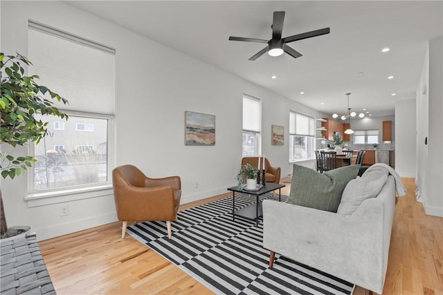 living area featuring a ceiling fan, baseboards, wood finished floors, and recessed lighting