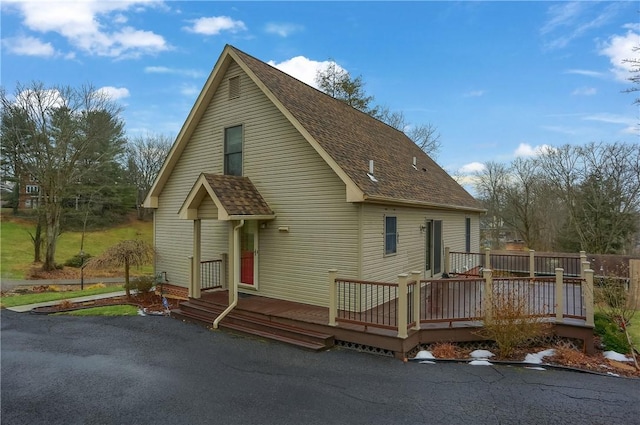 rear view of house with a shingled roof and a wooden deck