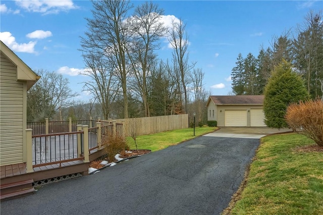 exterior space with a garage, a lawn, fence, and a wooden deck