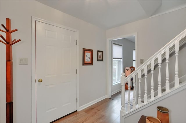 foyer entrance with light wood finished floors, stairway, and baseboards